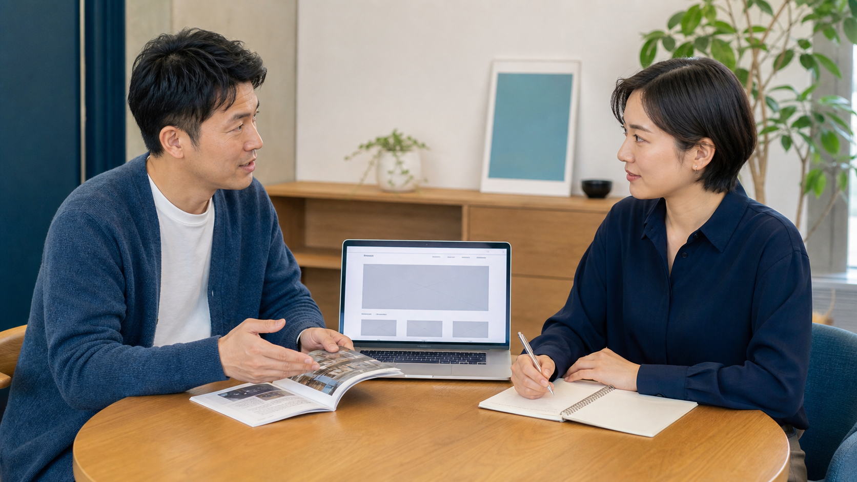 事業者がパンフレットを見せながら、制作担当者とホームページについて話すイメージ